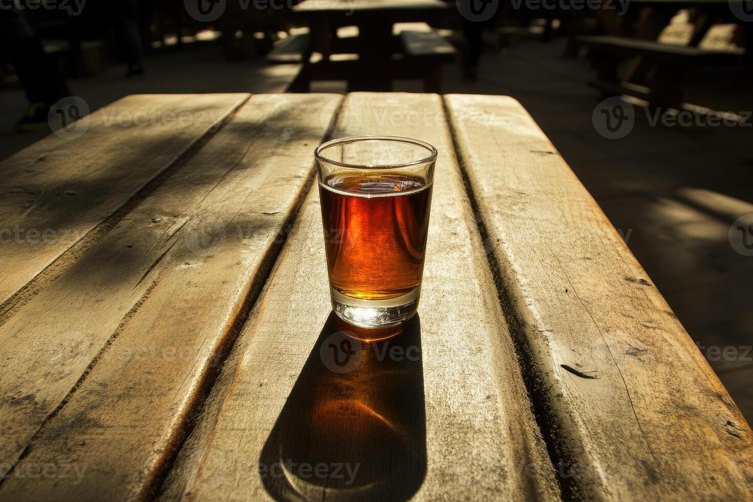 Amber beer in a glass on a wooden picnic table photo
