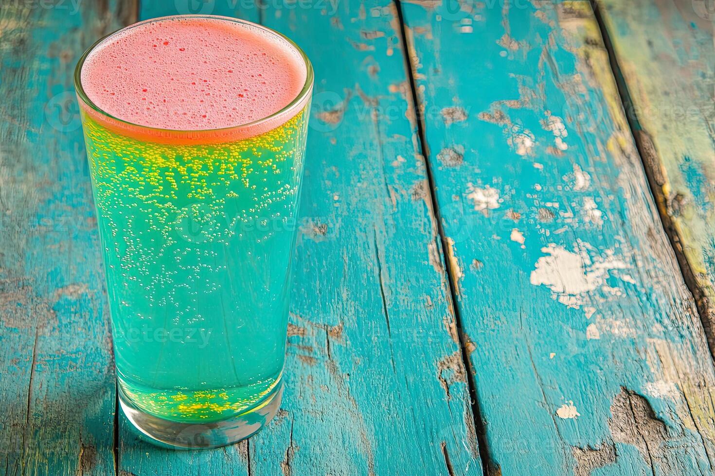 Vibrant, fizzy drink in glass on teal wood photo