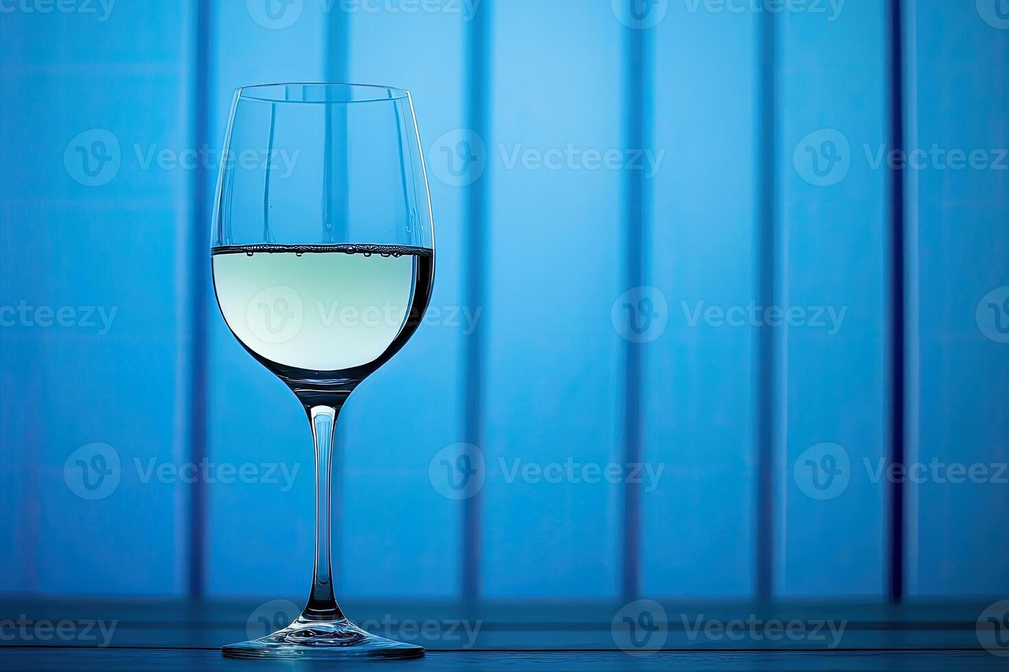 A glass of white wine against a blue background photo