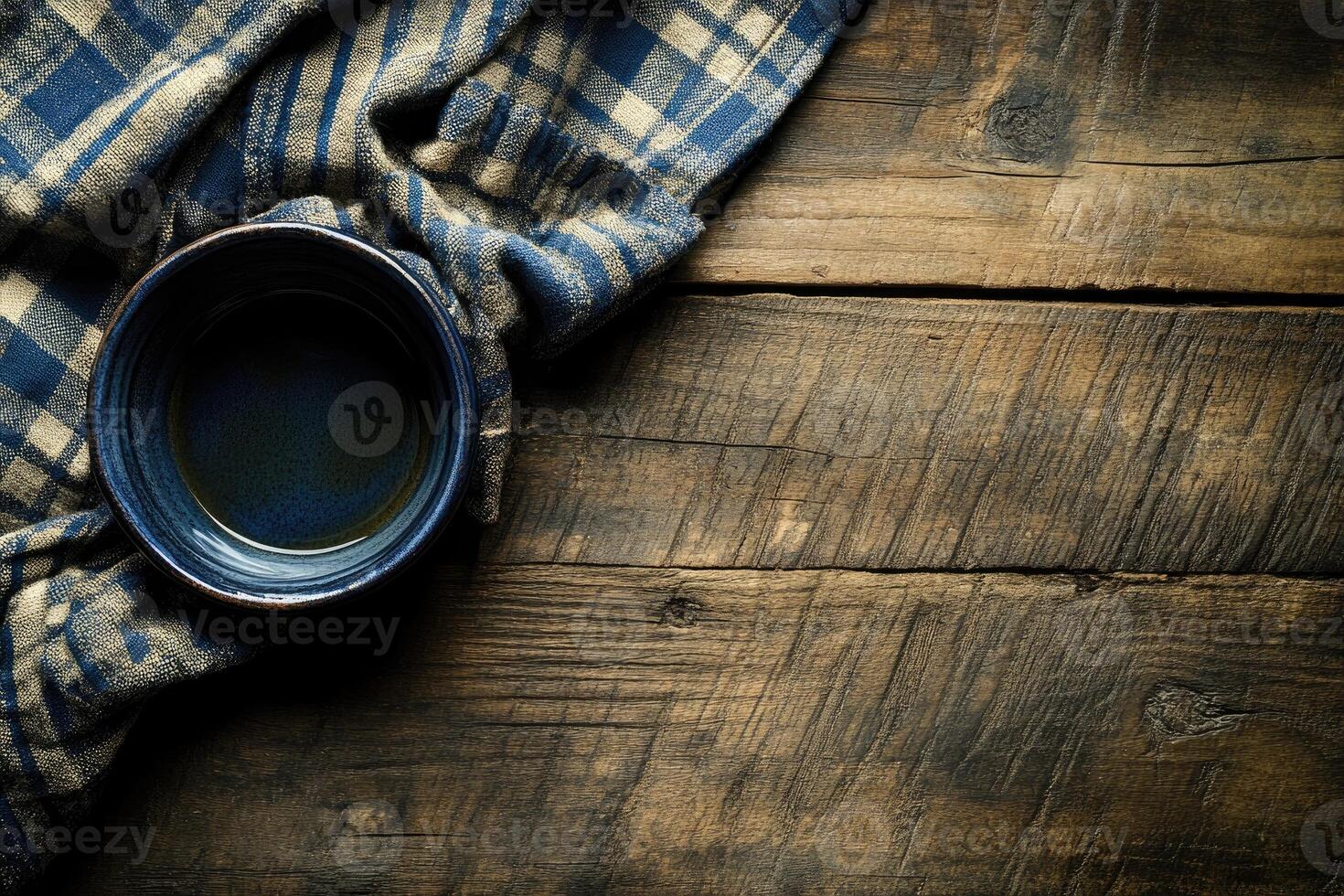 Empty dark blue bowl on rustic wooden table with checkered cloth photo