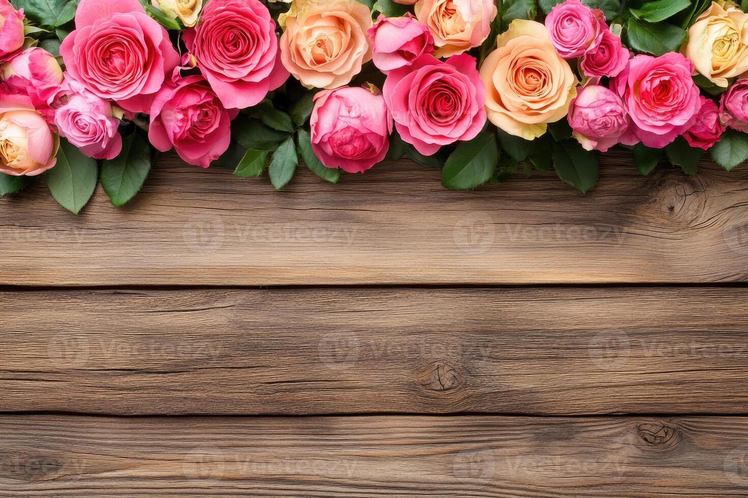 A horizontal border of various shades of pink and peach roses on a rustic wooden background photo