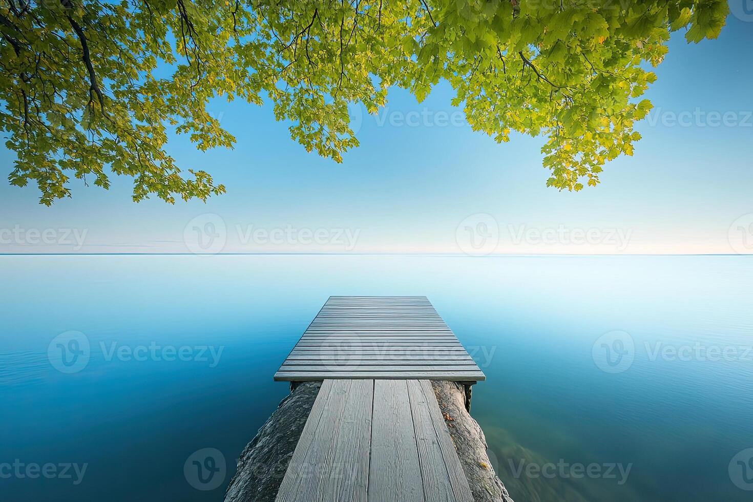 Tranquil lake dock at dawn. Lush foliage frames a serene dock over glassy water photo