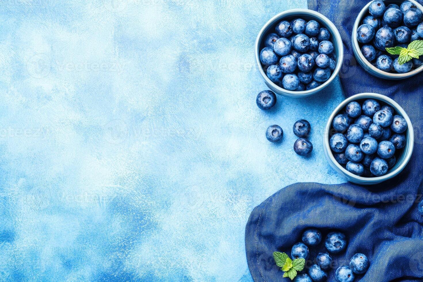 Fresh blueberries in bowls on a textured blue background photo