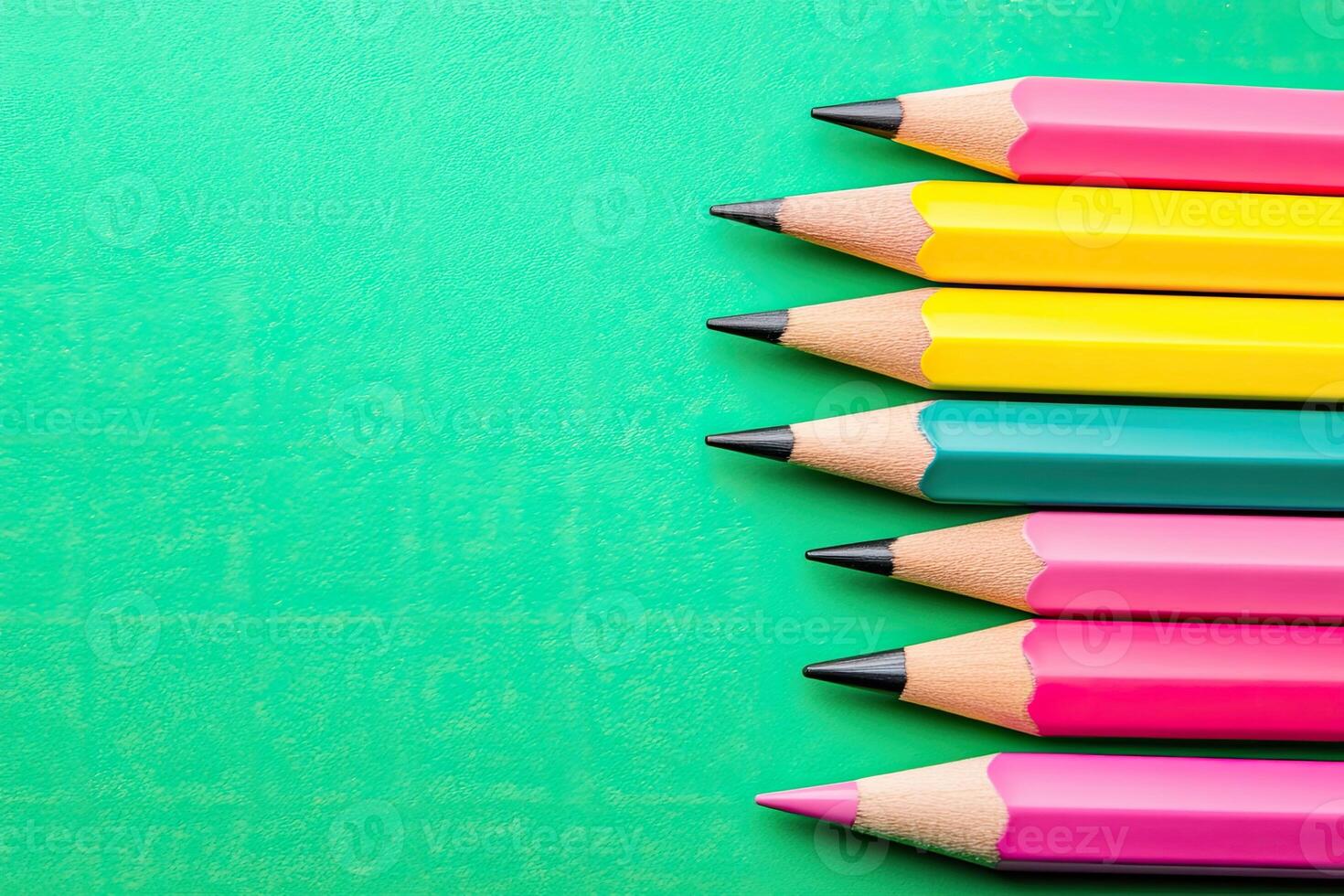 Colorful pencils arranged in a row against a vibrant green background photo