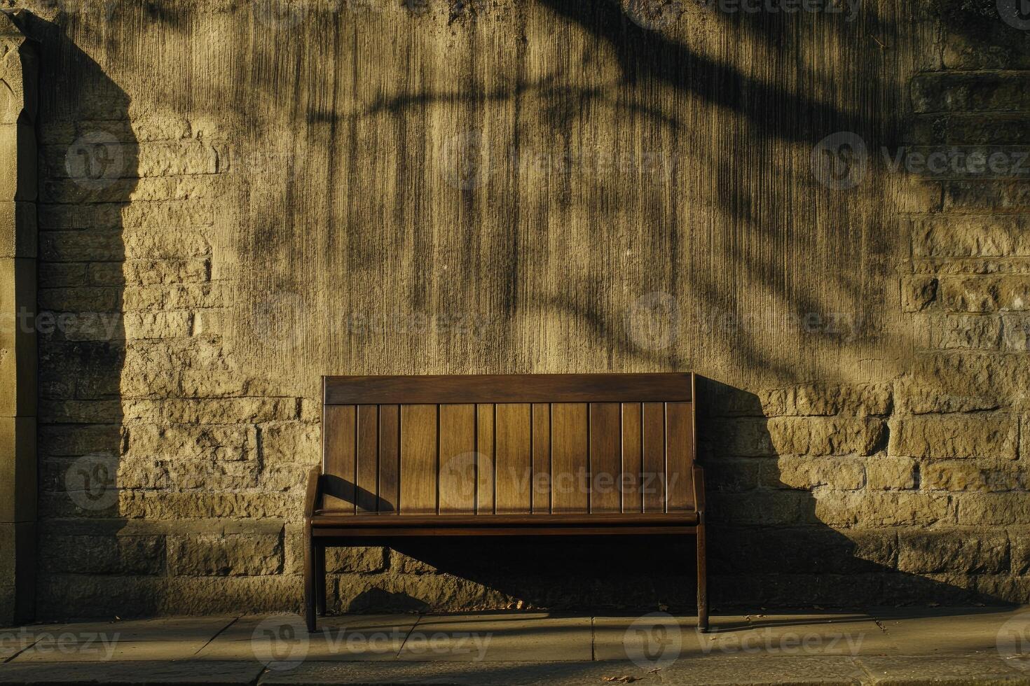 Simple wooden park bench against a weathered stone wall photo