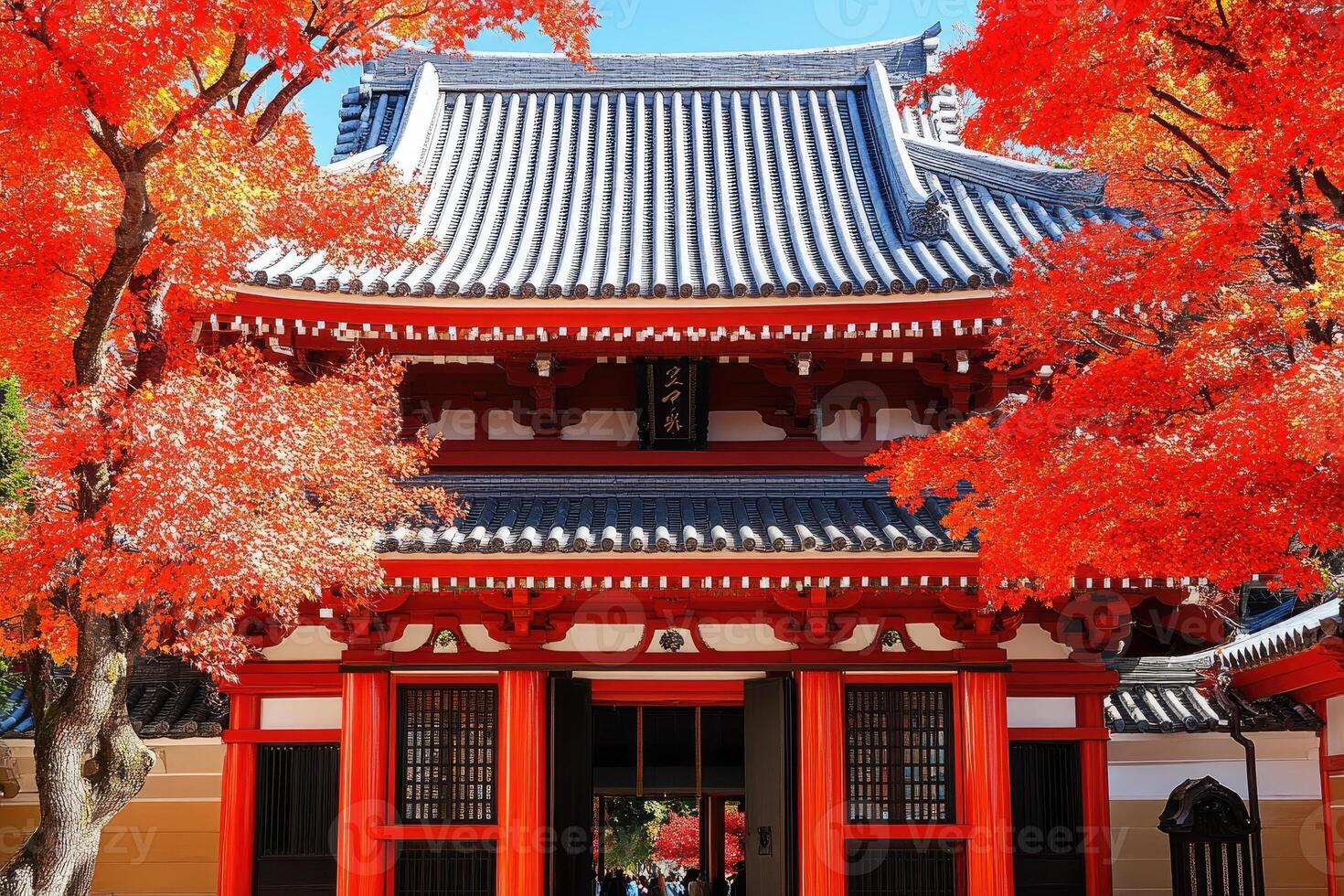 Autumnal Japanese temple facade. Vibrant fall foliage surrounds a traditional red and black building, with a distinctive, layered roof photo