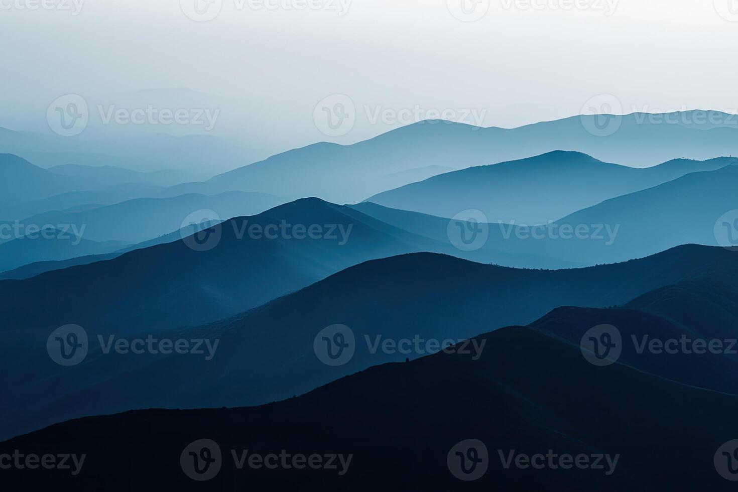 Misty mountain ranges layered in soft blues and deep shadows photo