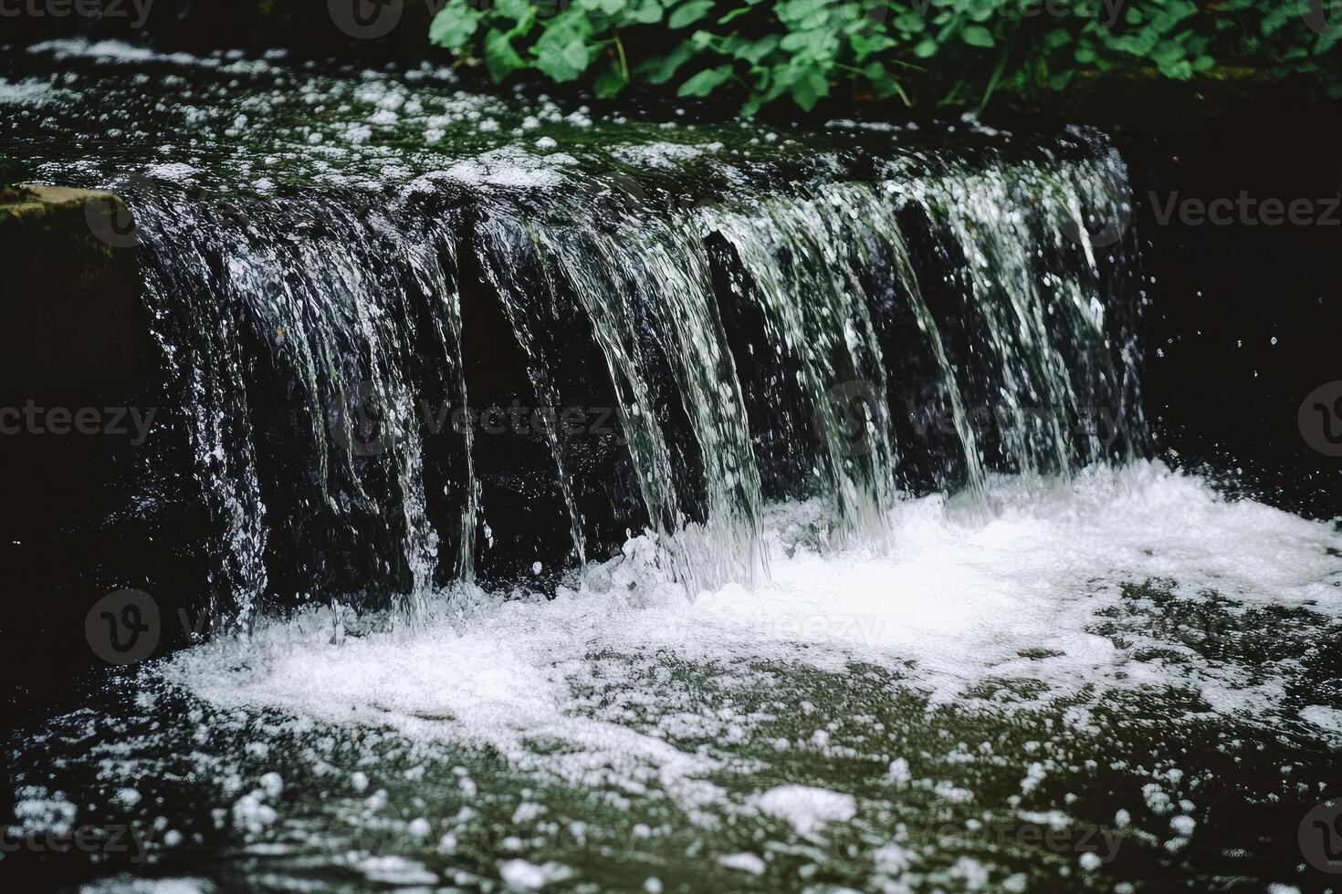Small waterfall cascading over dark stones photo