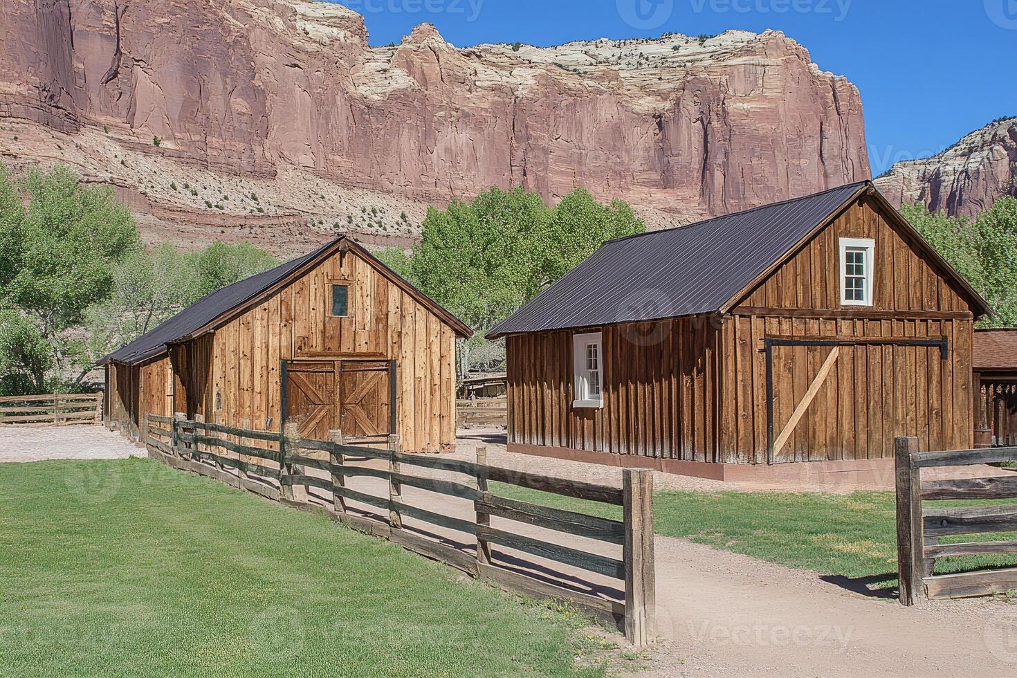 Rustic wooden barns nestled amongst red rock cliffs photo