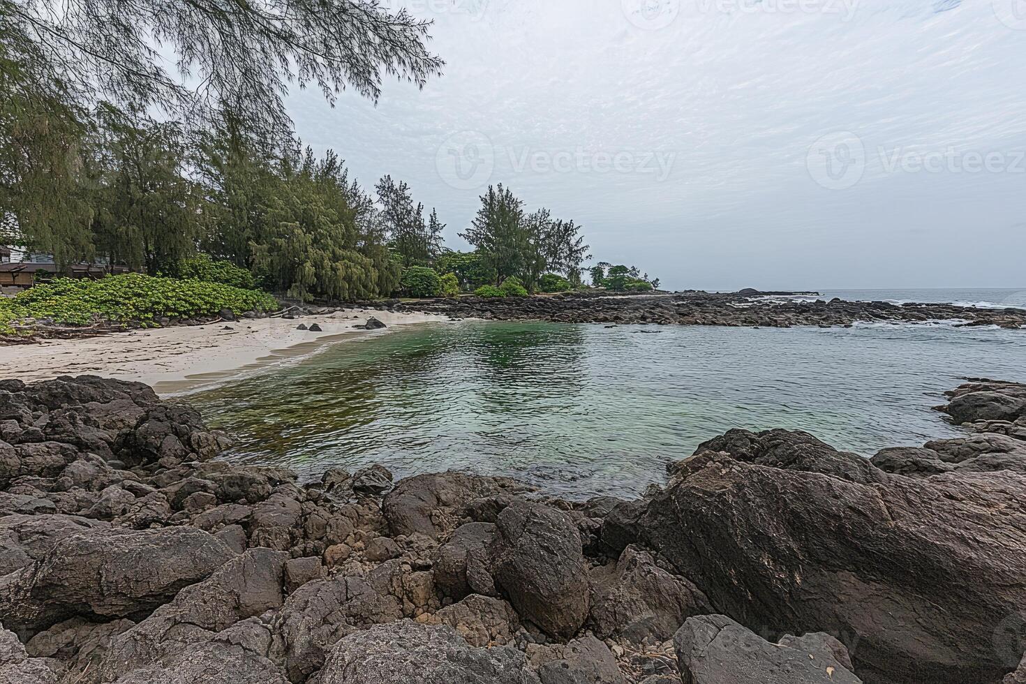 Tranquil cove bathed in soft light. Rocky shoreline meets calm turquoise water photo