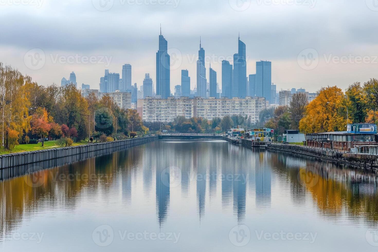 Autumn cityscape reflected in a calm river. Modern buildings mirrored in tranquil water, flanked by colorful fall foliage photo