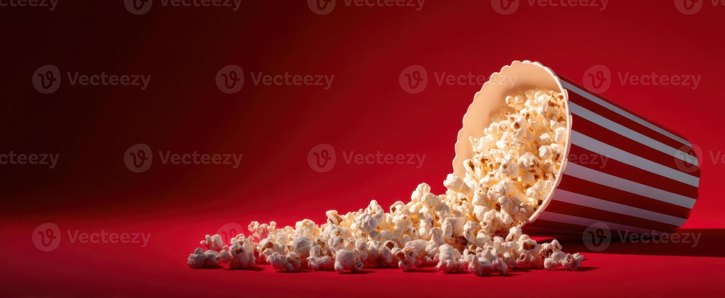 The overflowing popcorn container against a vibrant red background. photo