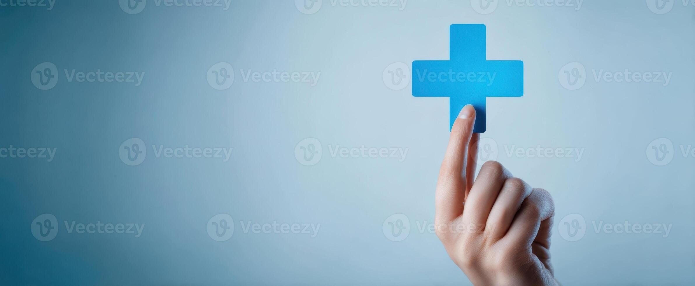 The hand pointing at a blue medical plus sign against a serene background. photo