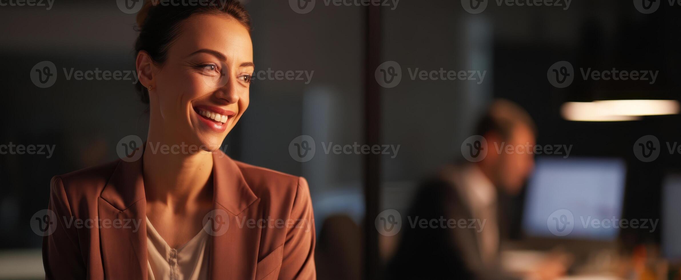The confident woman smiling in an elegant office setting during evening work hours. photo
