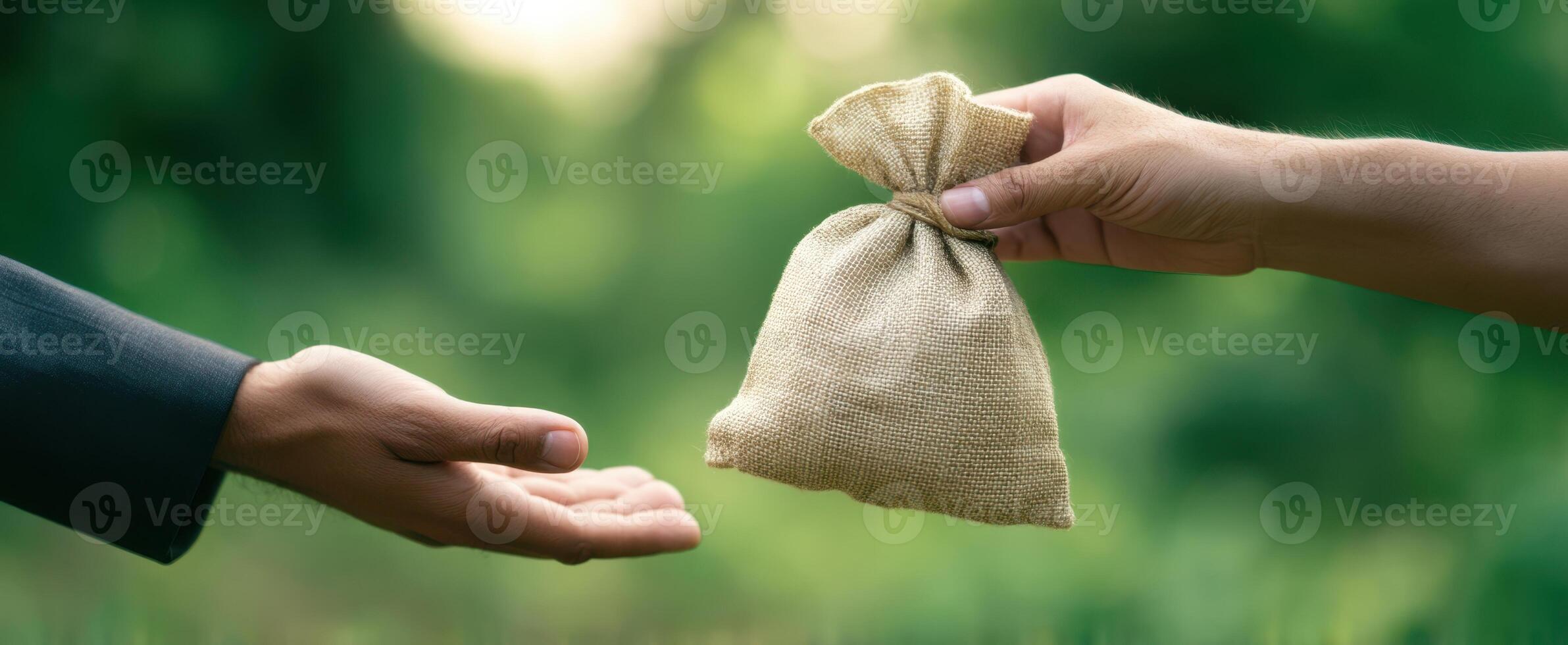 The hands exchanging a burlap bag representing a financial transaction outdoors. photo