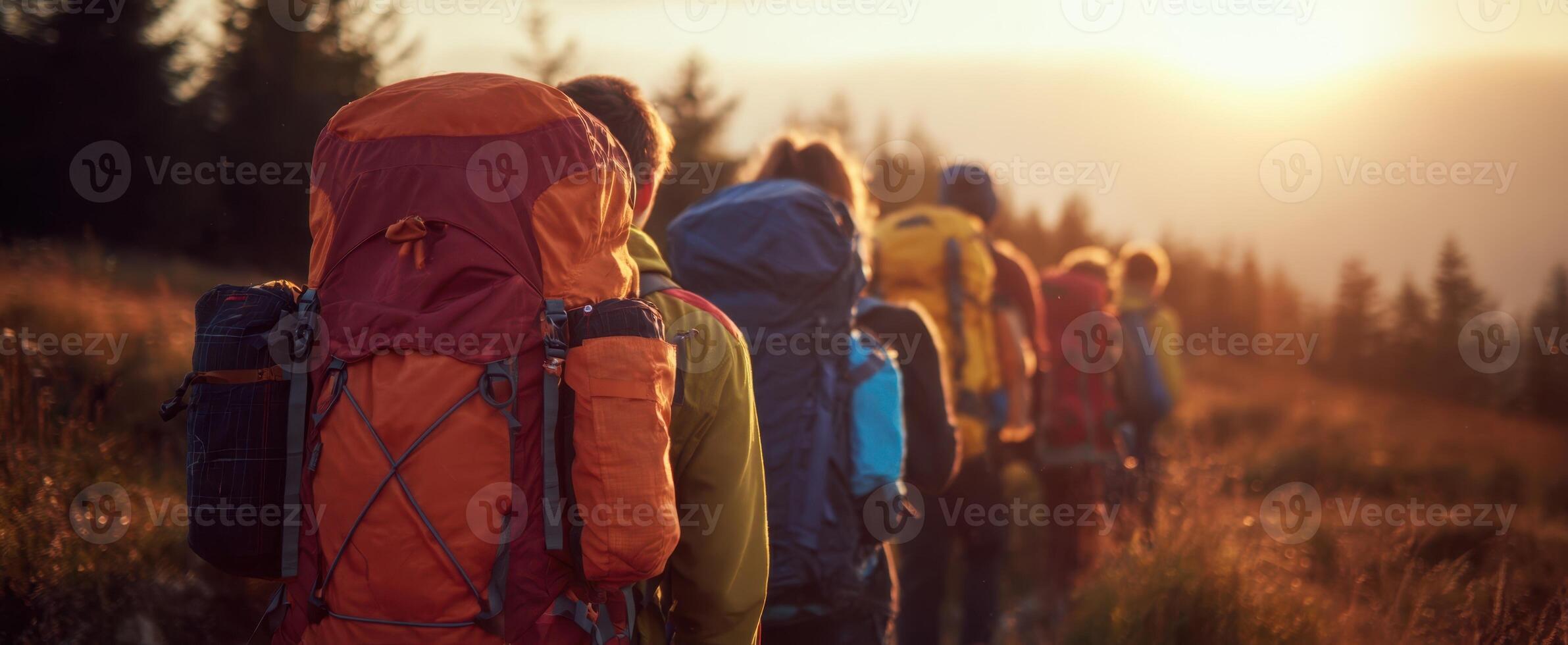 The hikers trekking along a scenic trail at sunset in the mountains. photo