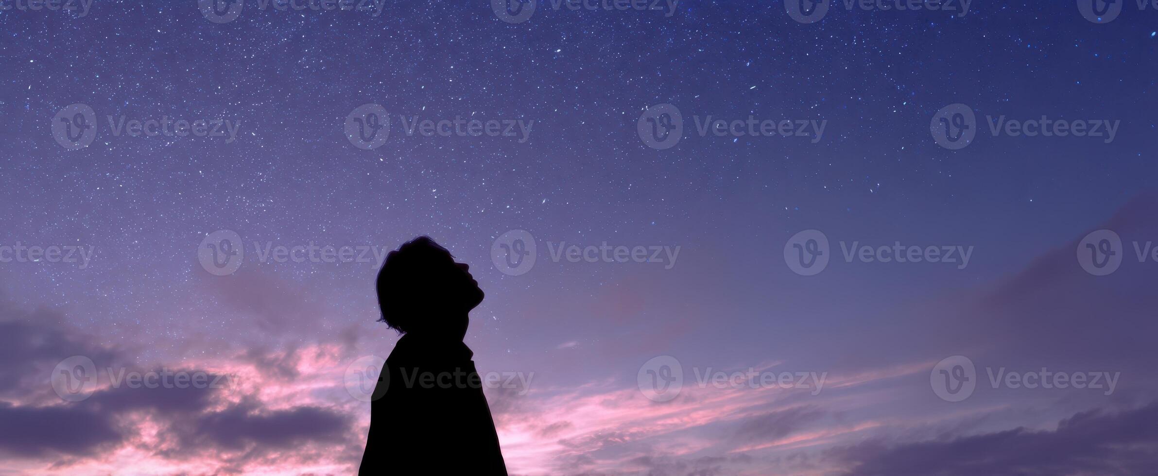 The silhouette of a person gazing at a starry night sky. photo