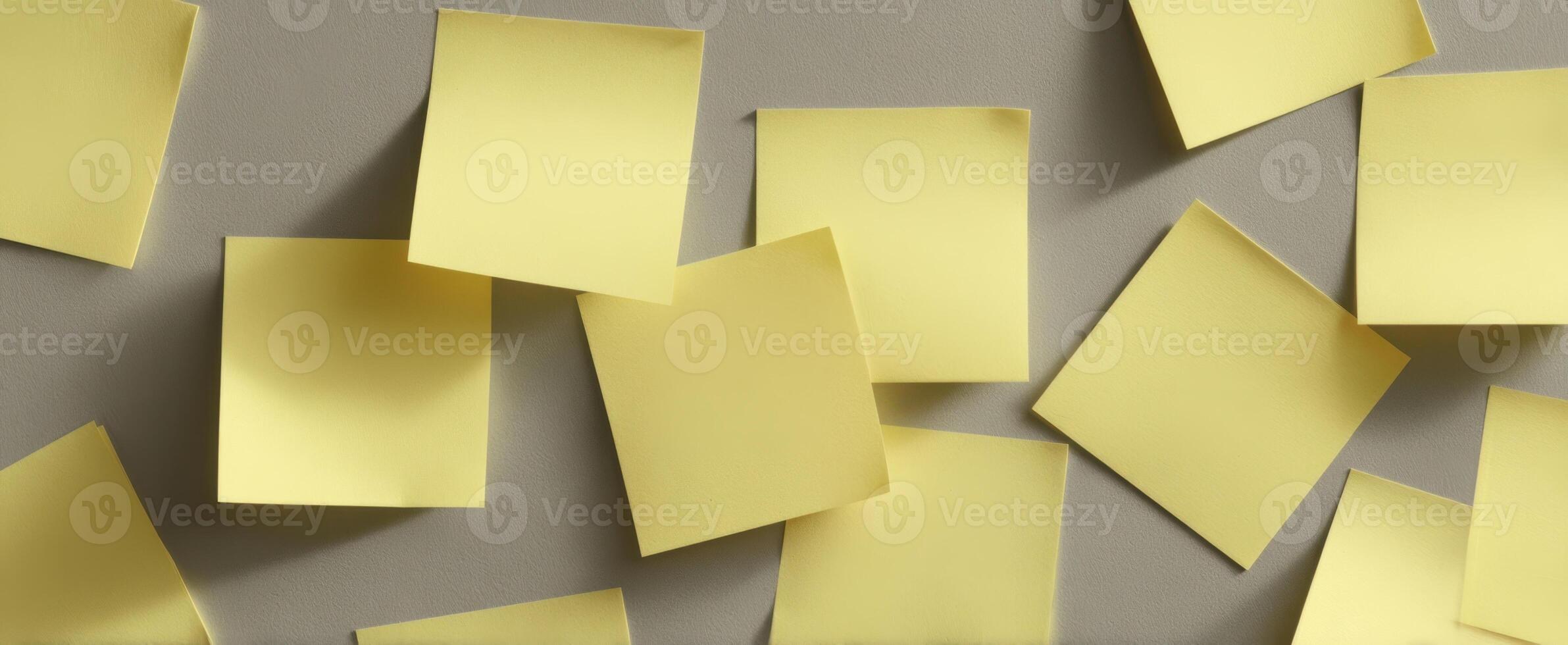 The scattered arrangement of yellow post-it notes on a grey background. photo