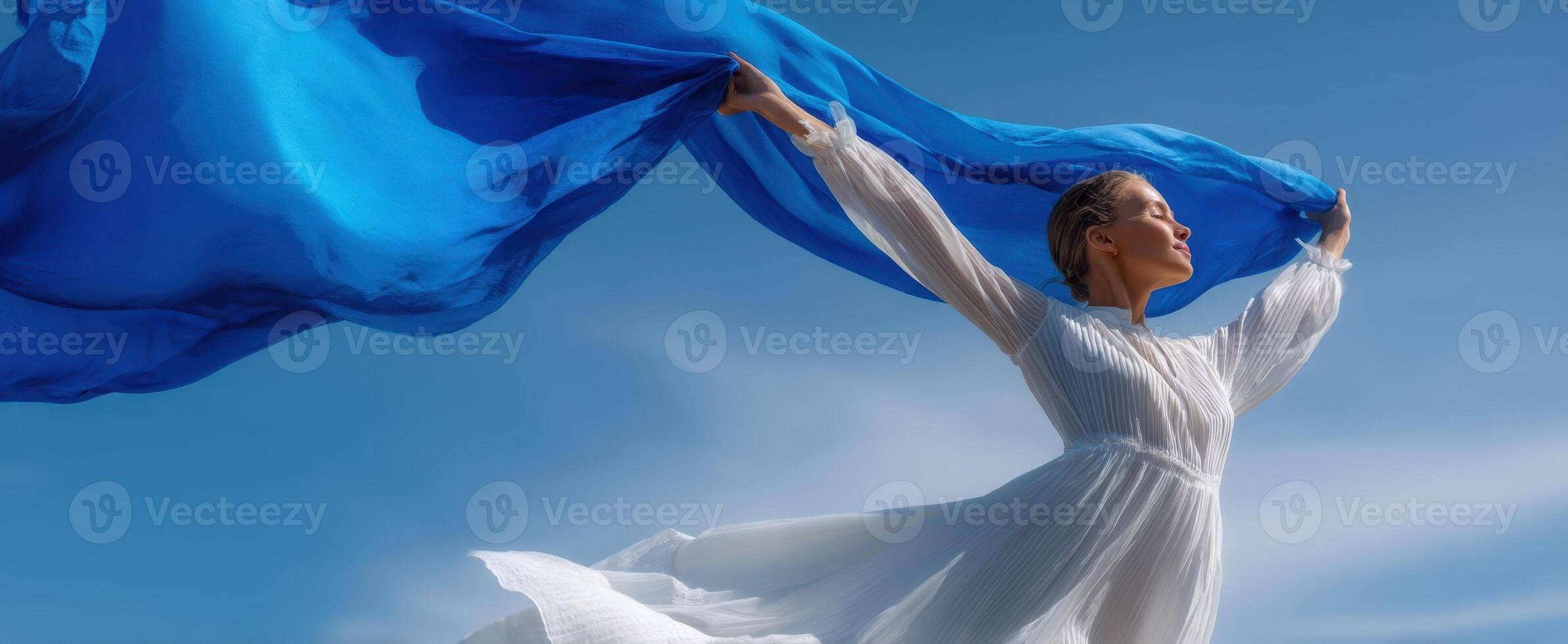 The graceful woman in a flowing blue fabric against a beautiful sky. photo