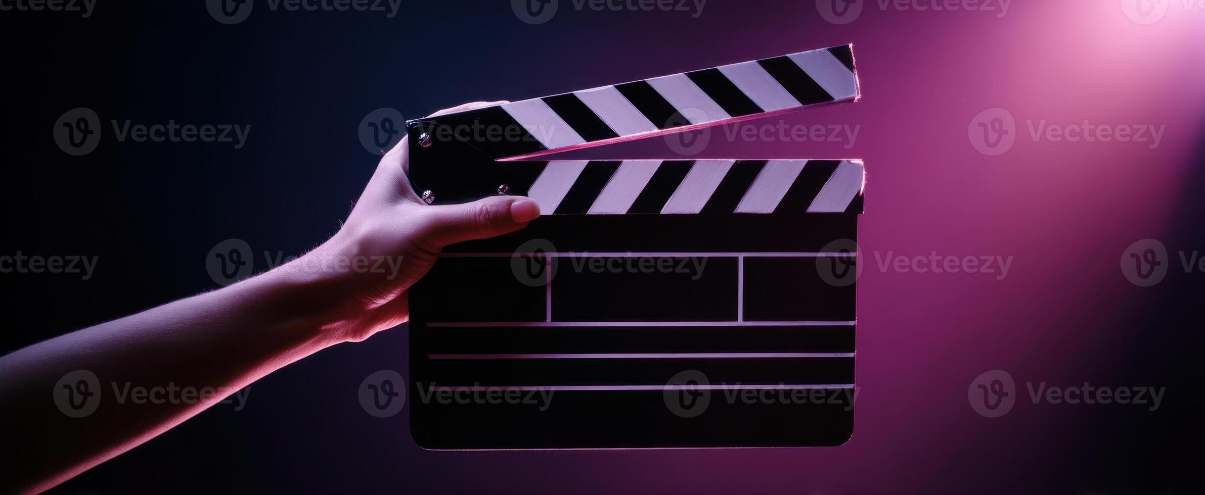 The clapperboard held in a hand against a colorful background of light. photo