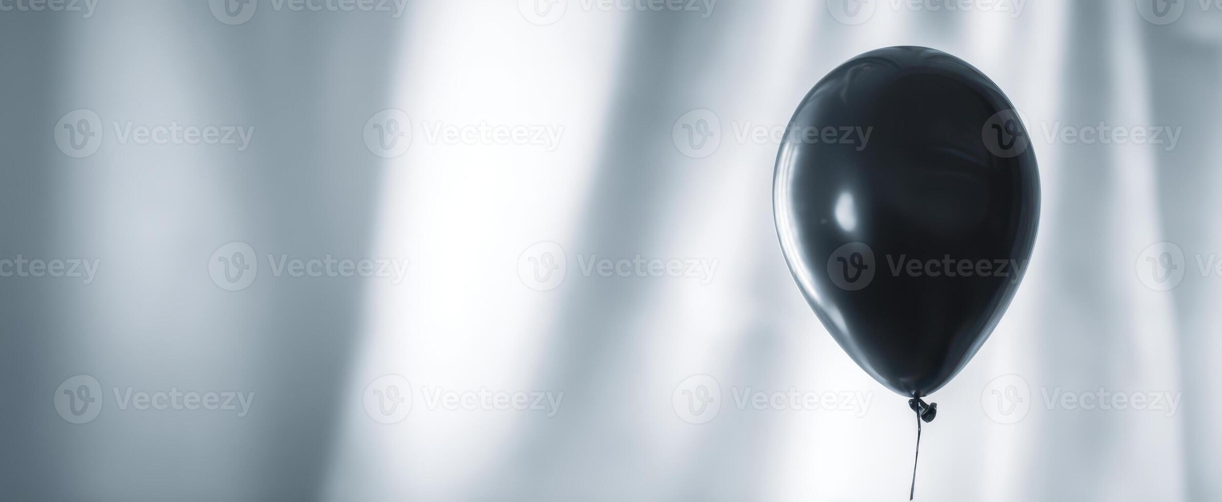 The black balloon floating against a minimalist background of light and shadow. photo