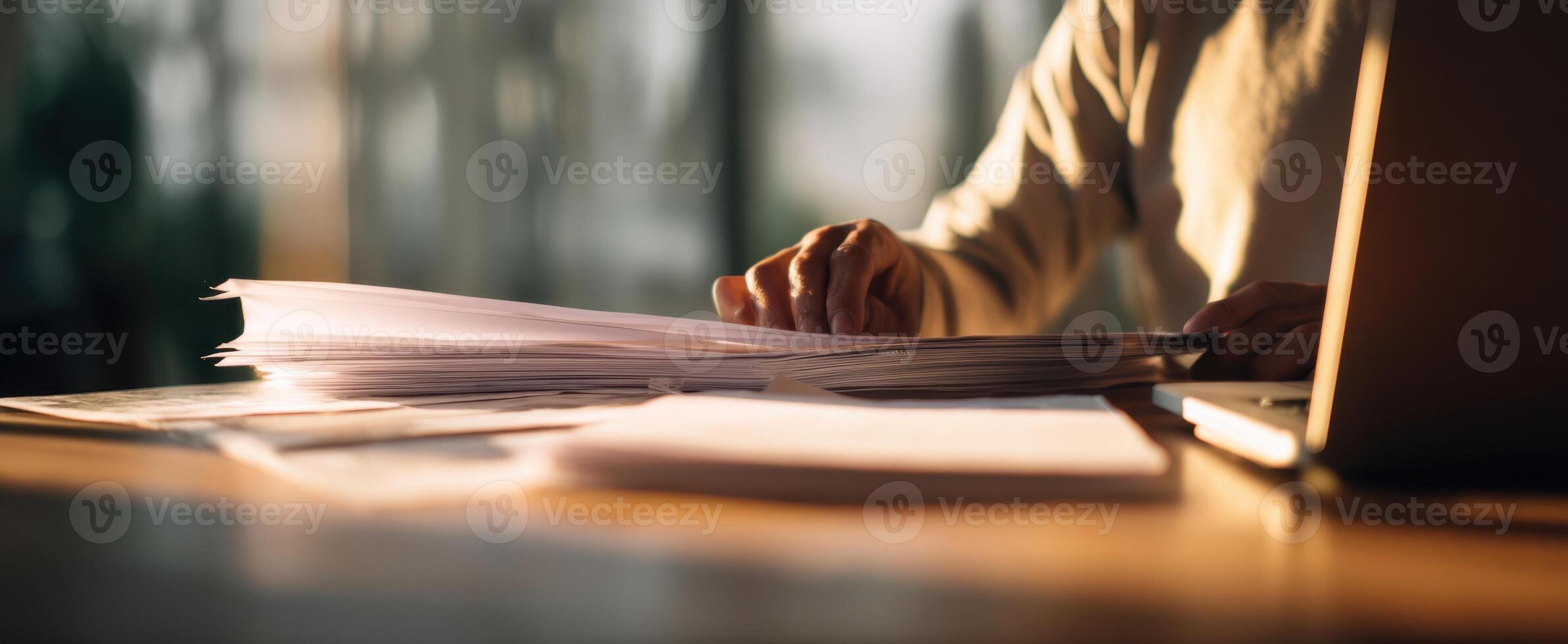 The person organizing paperwork at a modern workspace in soft lighting. photo