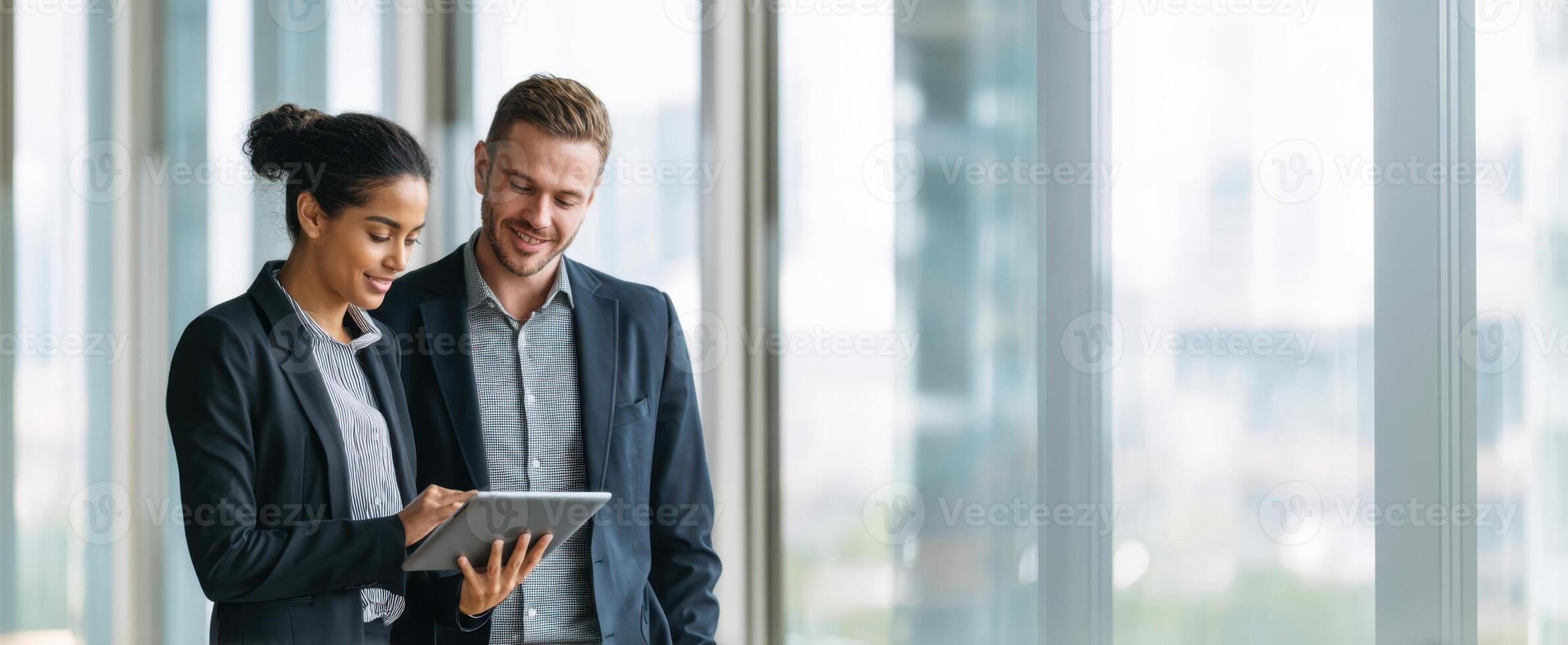 The professionals collaborating while reviewing digital content on a tablet in an office setting. photo