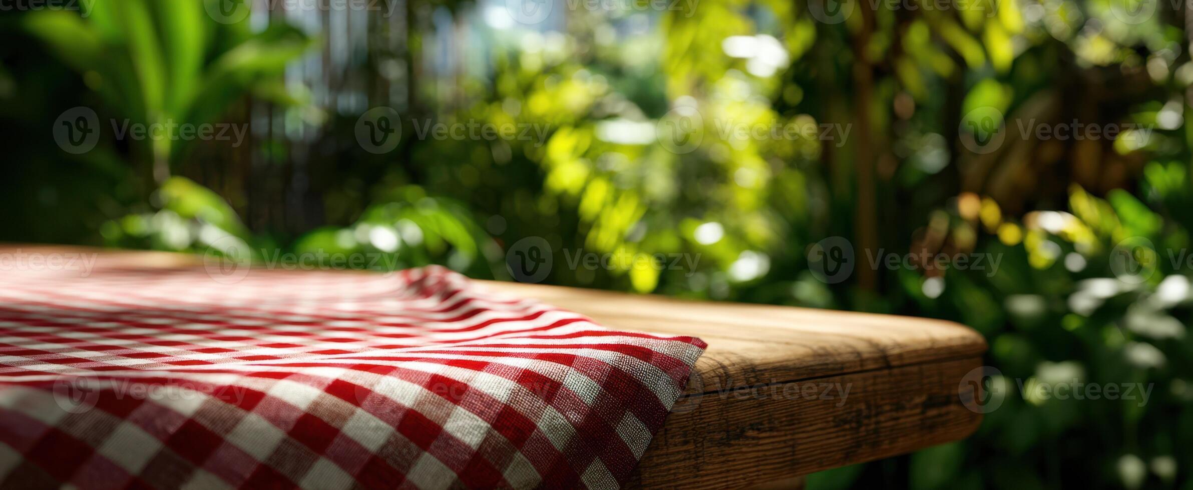 The rustic table adorned with checkered cloth amidst lush greenery and sunlight. photo