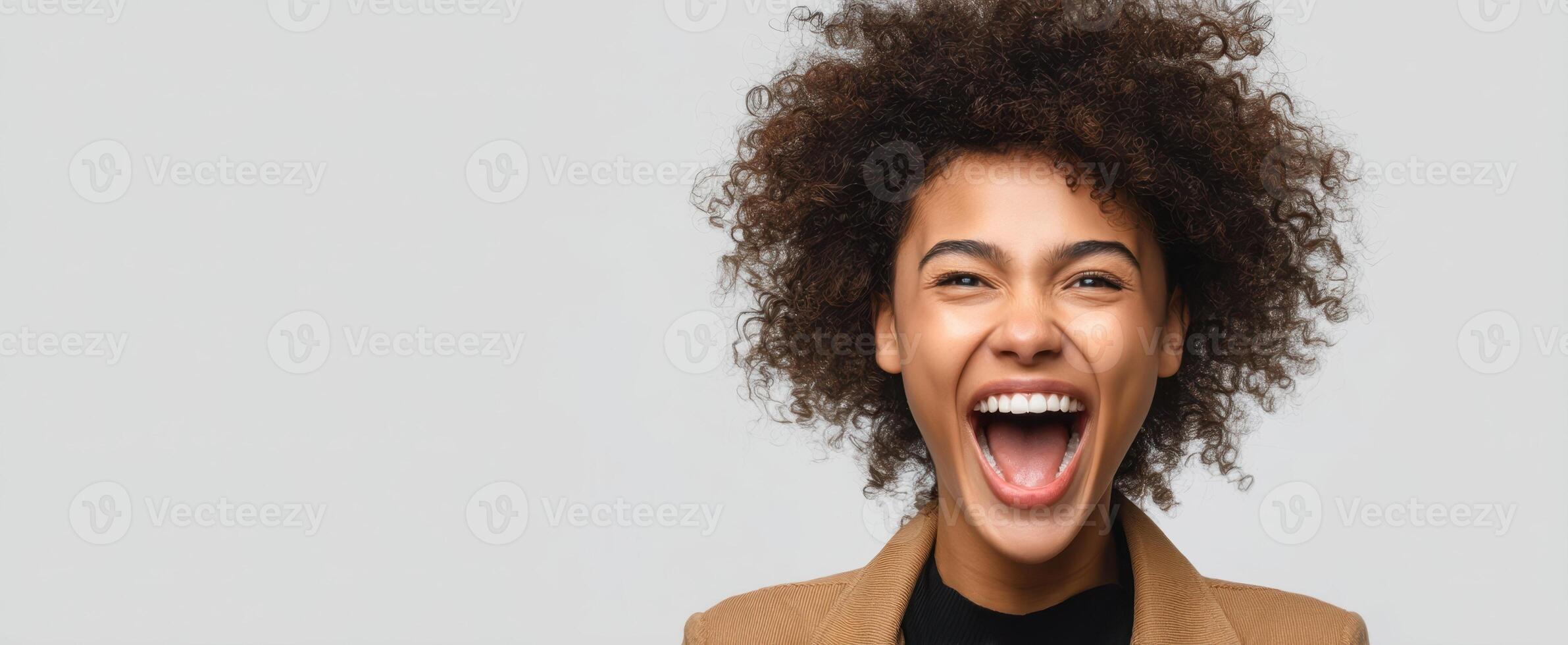 The joyful woman with curly hair expressing happiness and excitement in a studio setting. photo