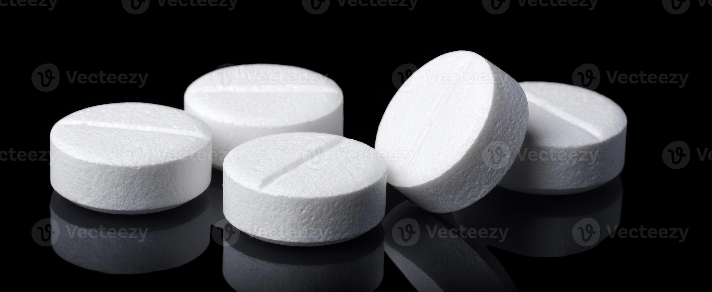 The collection of white tablets reflecting elegantly on a black surface. photo