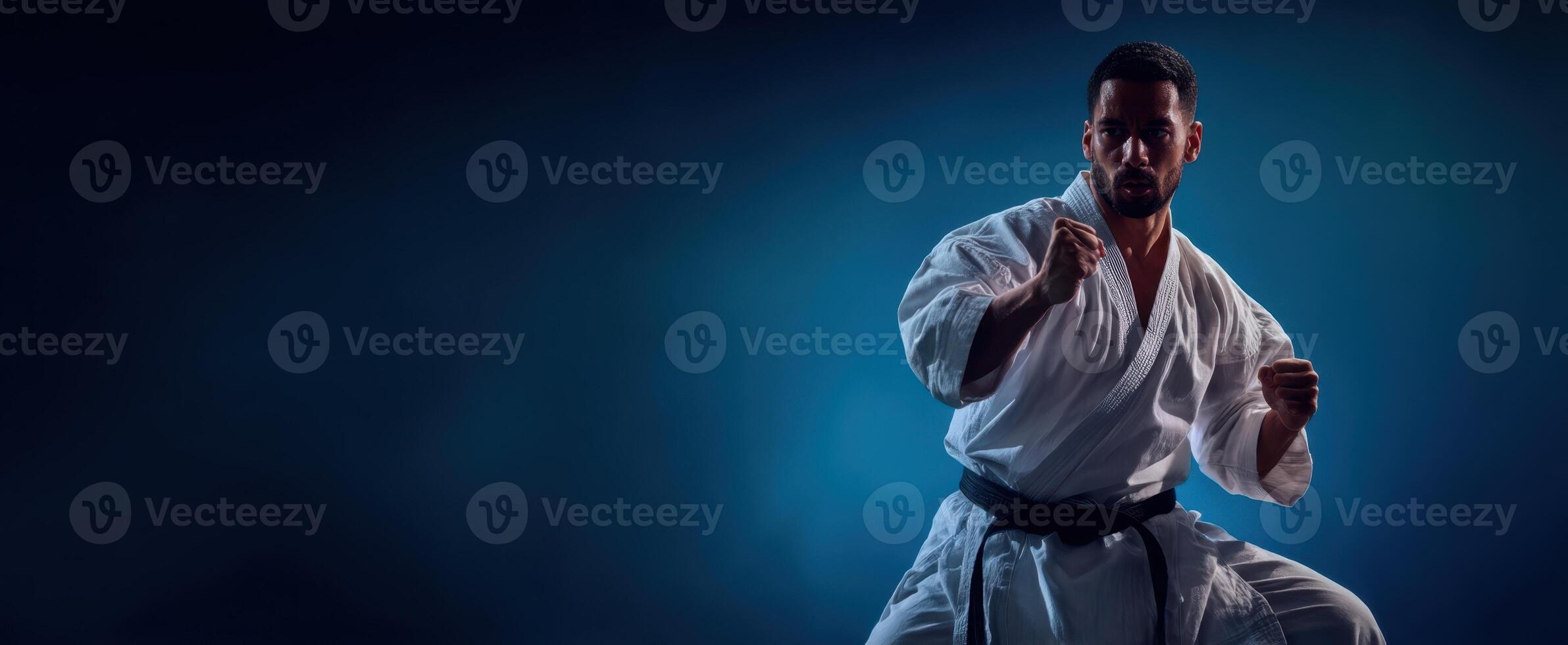The karate fighter showcasing strength and focus in a dramatic pose. photo