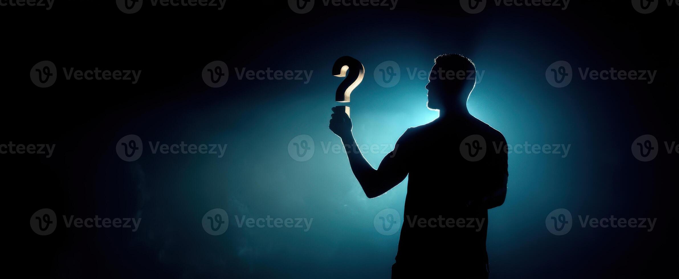 The silhouette holding a question mark in a dramatic light setting. photo
