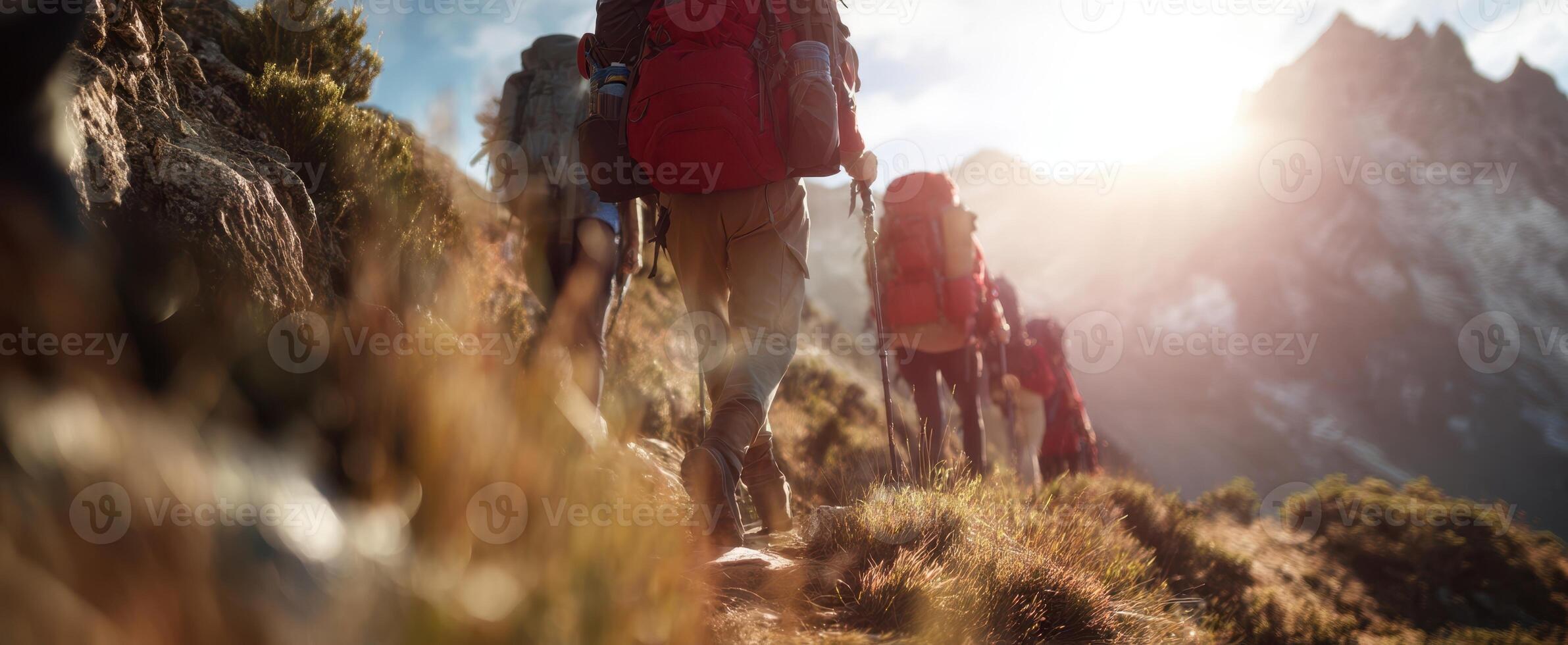 The hikers climbing towards a stunning mountain range at sunset. photo