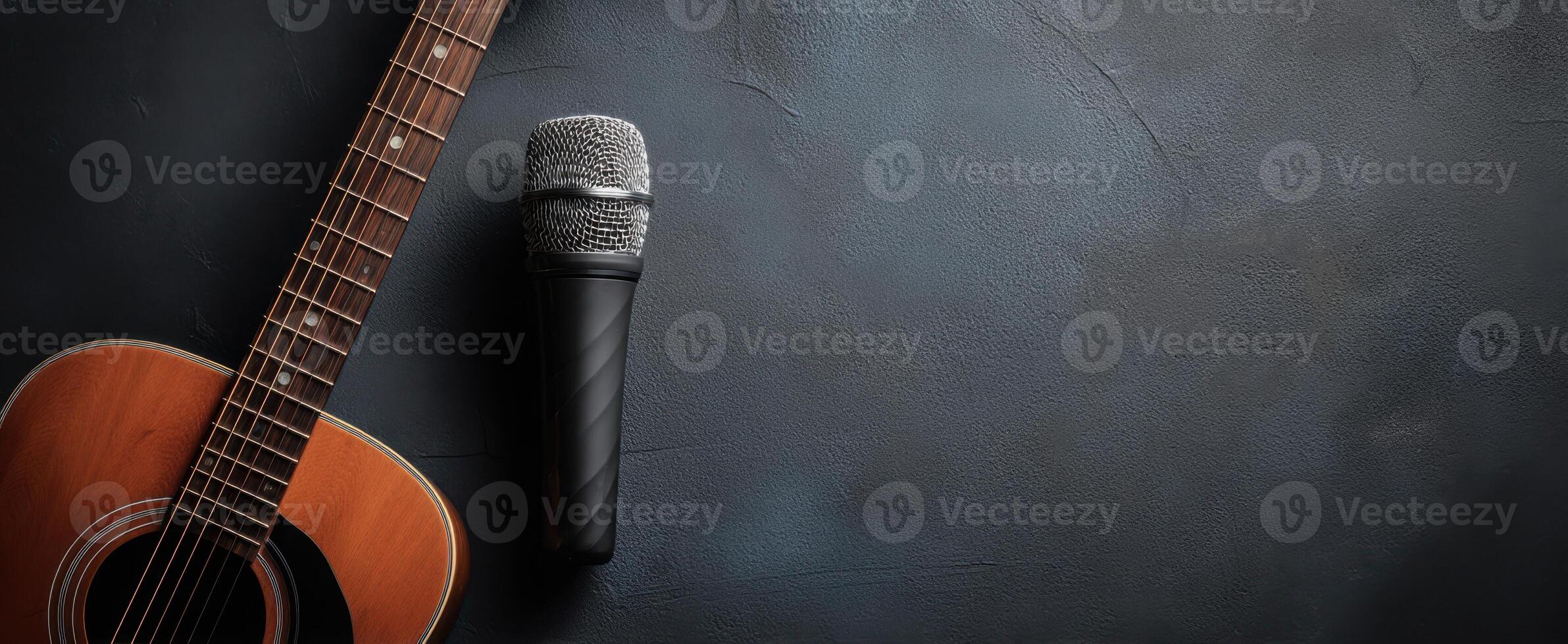 The acoustic guitar and microphone set against a dark background for music events. photo