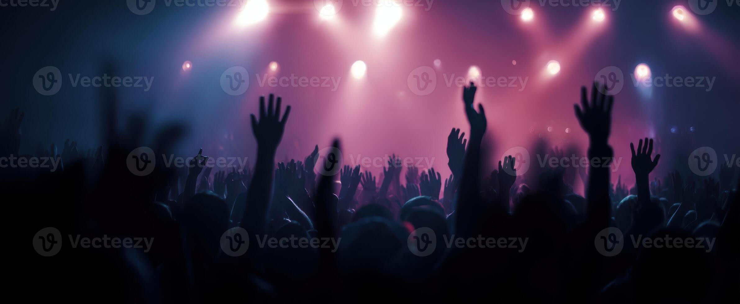The crowd celebrating at a vibrant live concert with raised hands. photo