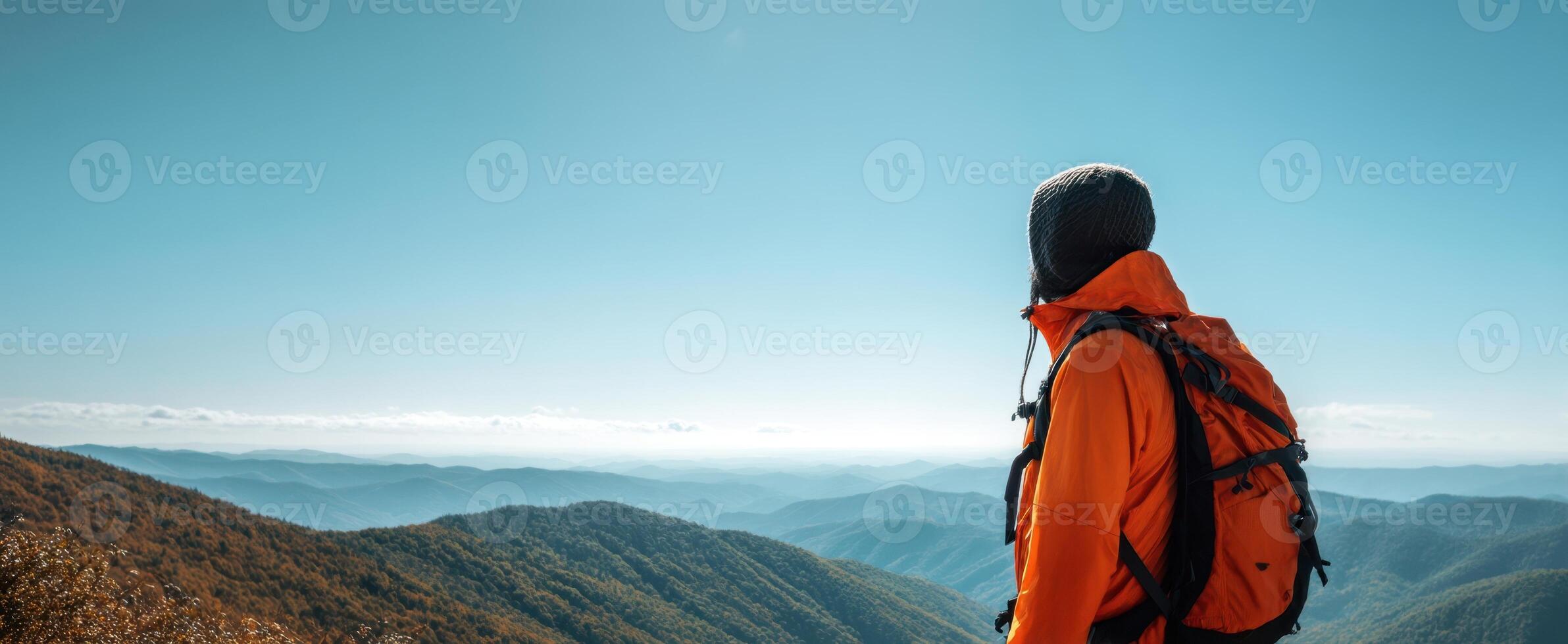 The adventurous hiker overlooking stunning mountain vistas under a clear blue sky. photo