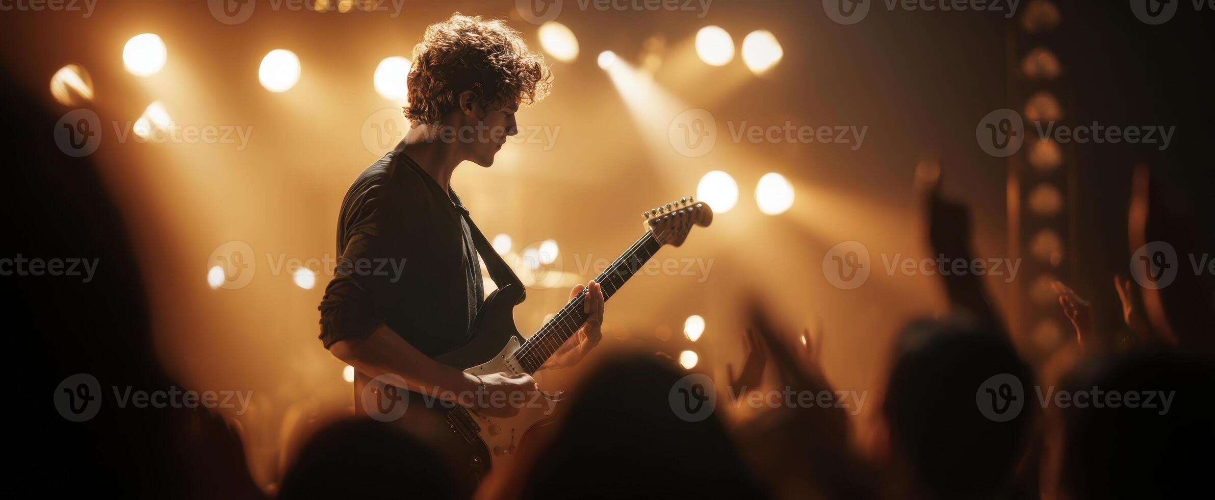 The guitarist performing passionately under vibrant stage lights at a live concert. photo