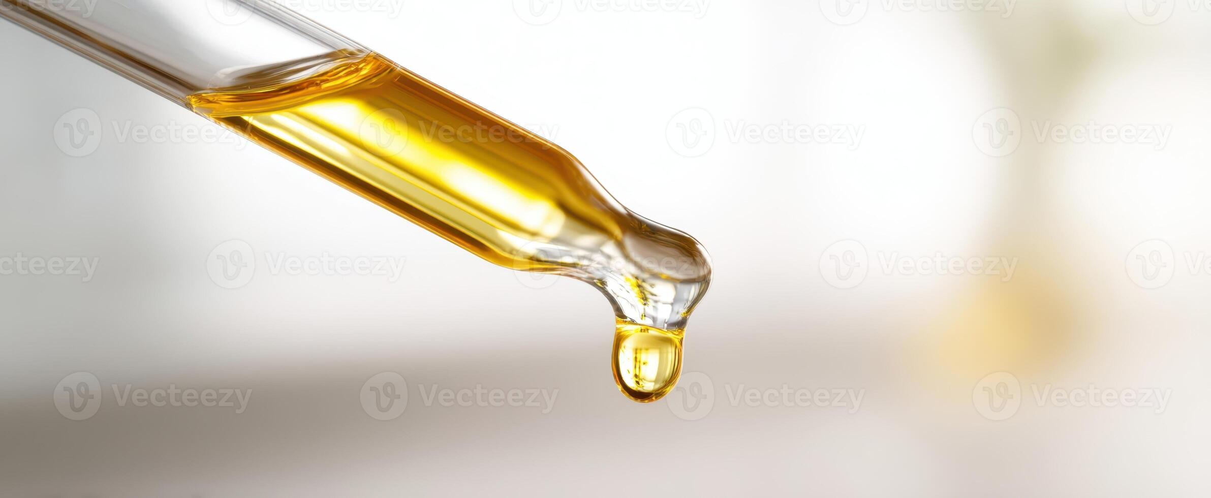 The droplet of golden essential oil captured in a glass pipette. photo