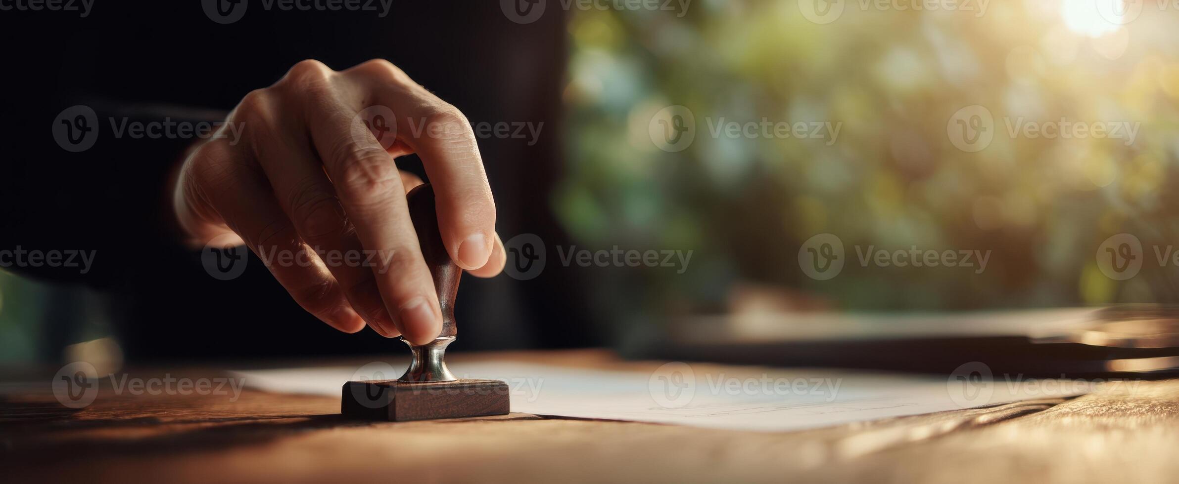 The hand applying a seal stamp over important documents on a wooden desk. photo