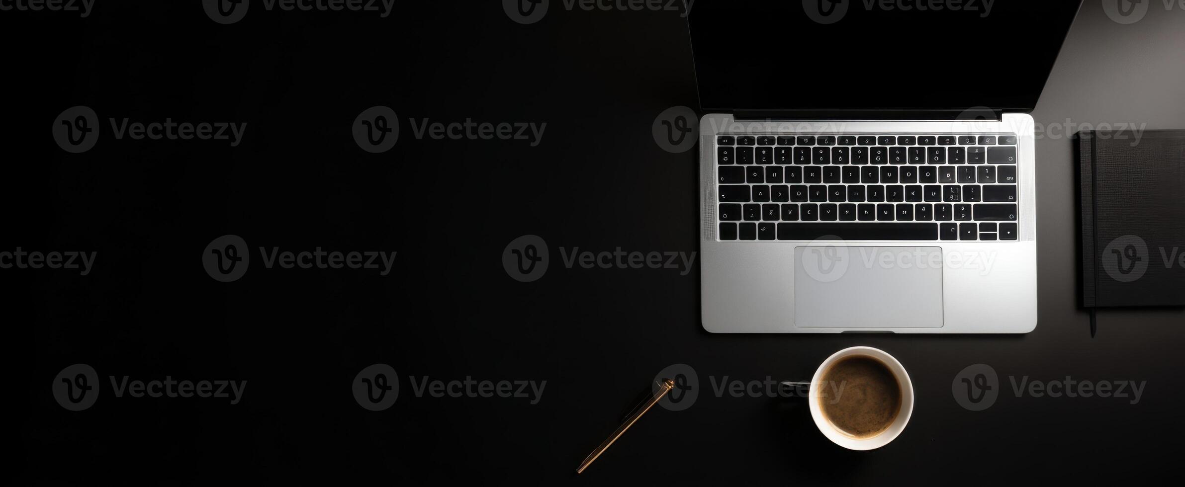 The Stylish Workspace Featuring a Laptop, Coffee, and Notebook on a Dark Surface photo