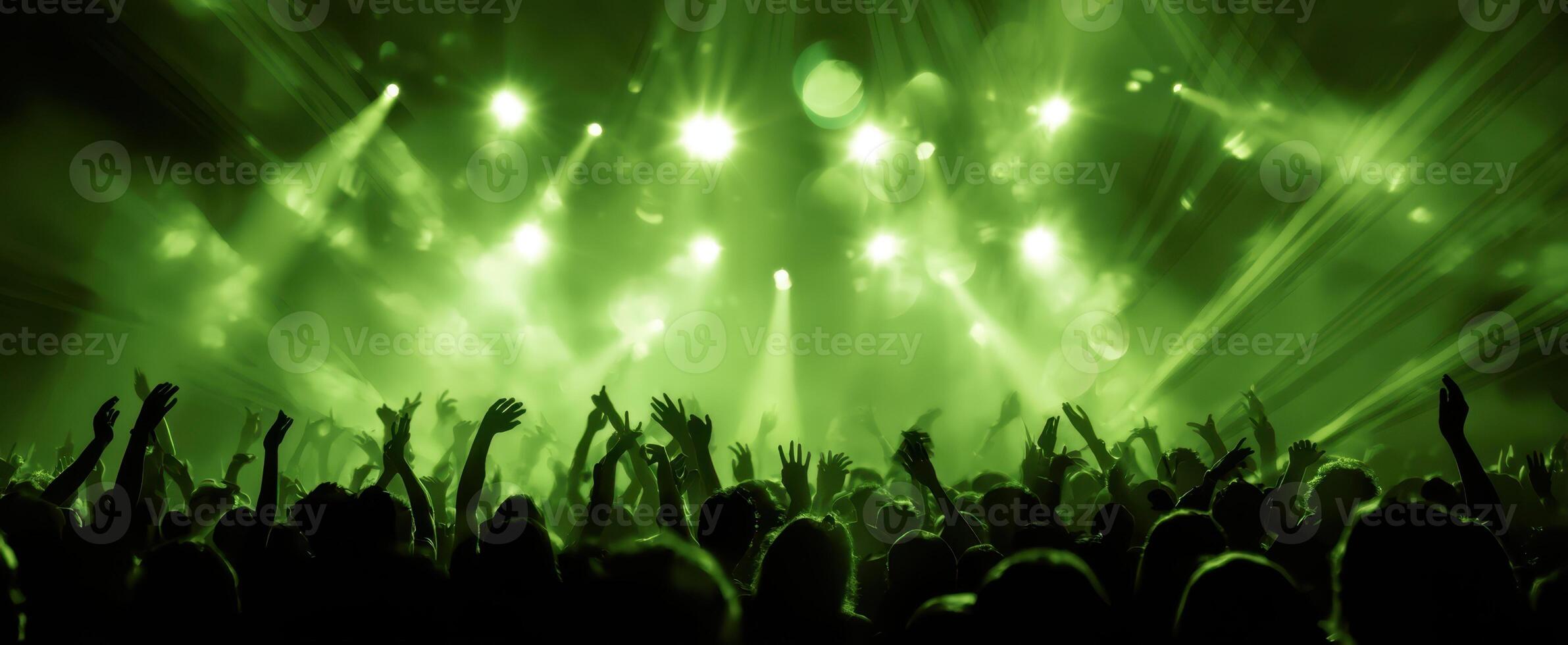 The vibrant crowd enjoying a dynamic concert experience with green lights. photo
