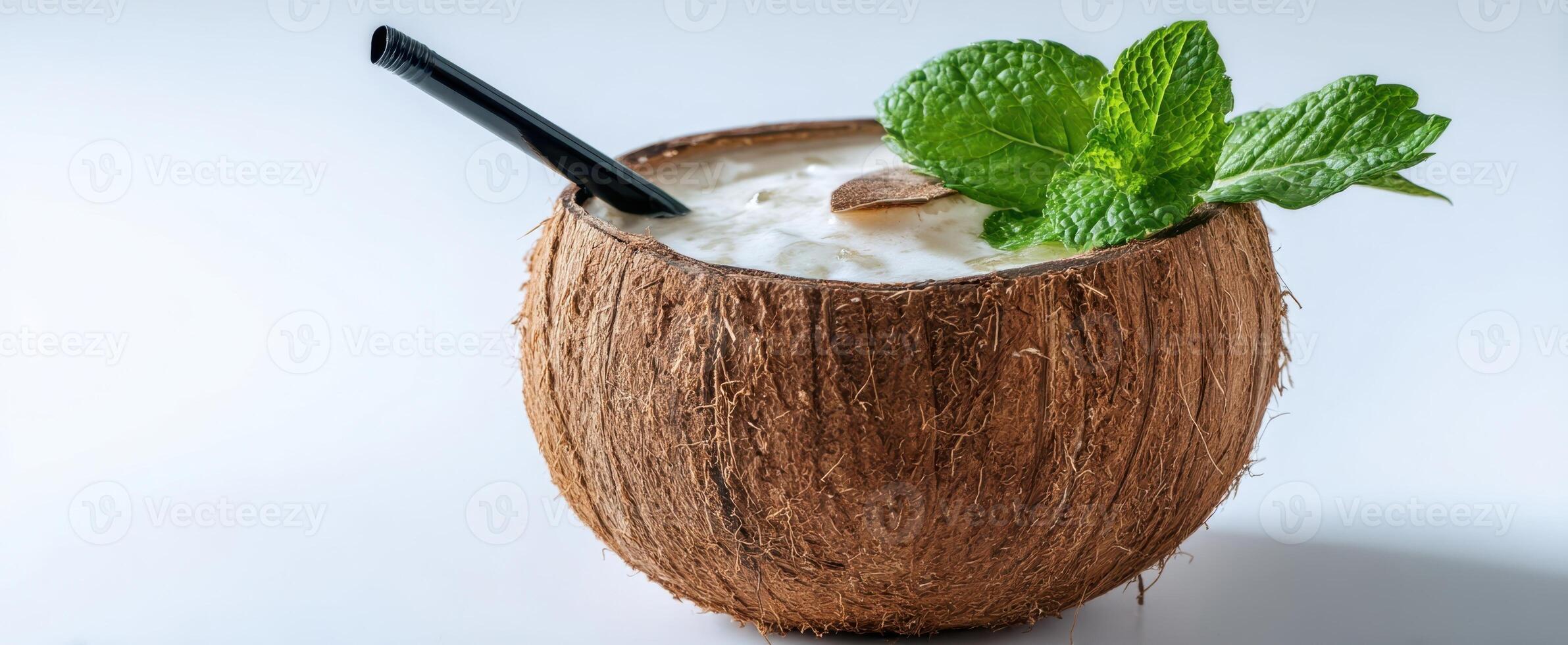The refreshing coconut drink garnished with mint and served in a natural shell. photo