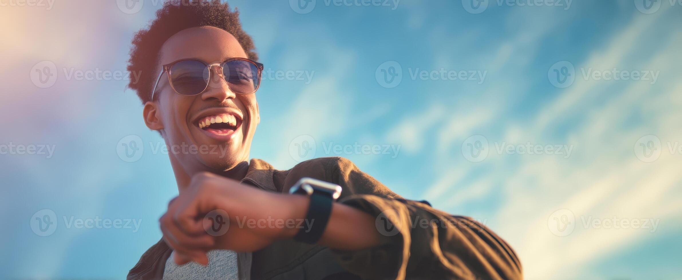 The joyful young man checking his watch under a clear blue sky. photo