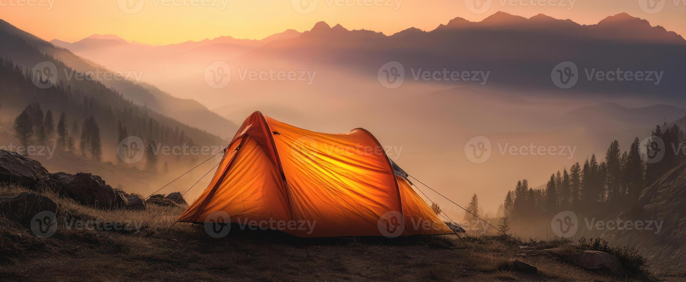 The vibrant orange tent silhouetted against a breathtaking mountain sunset. photo