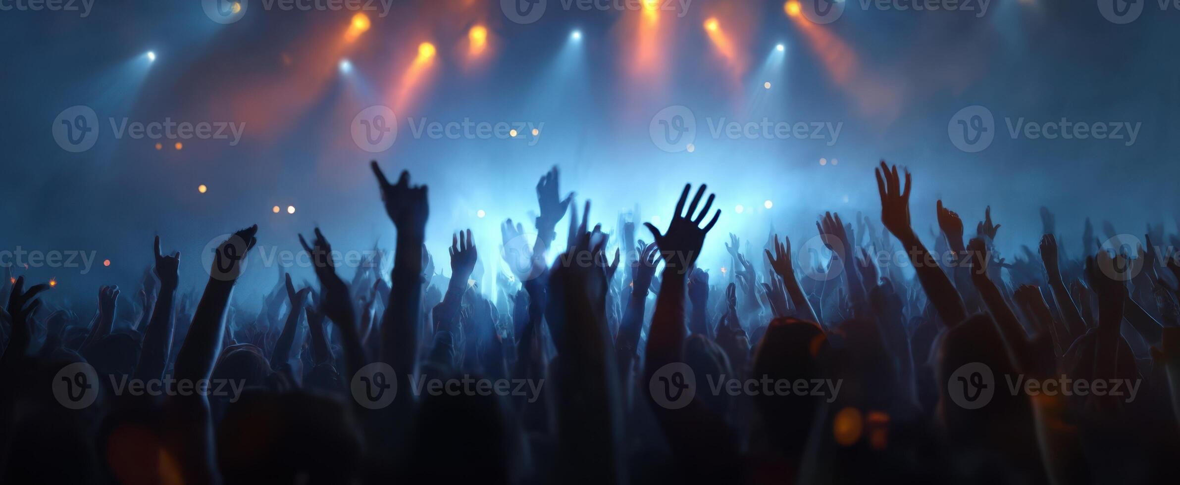 The enthusiastic crowd enjoying a live concert with raised hands and vibrant lights. photo