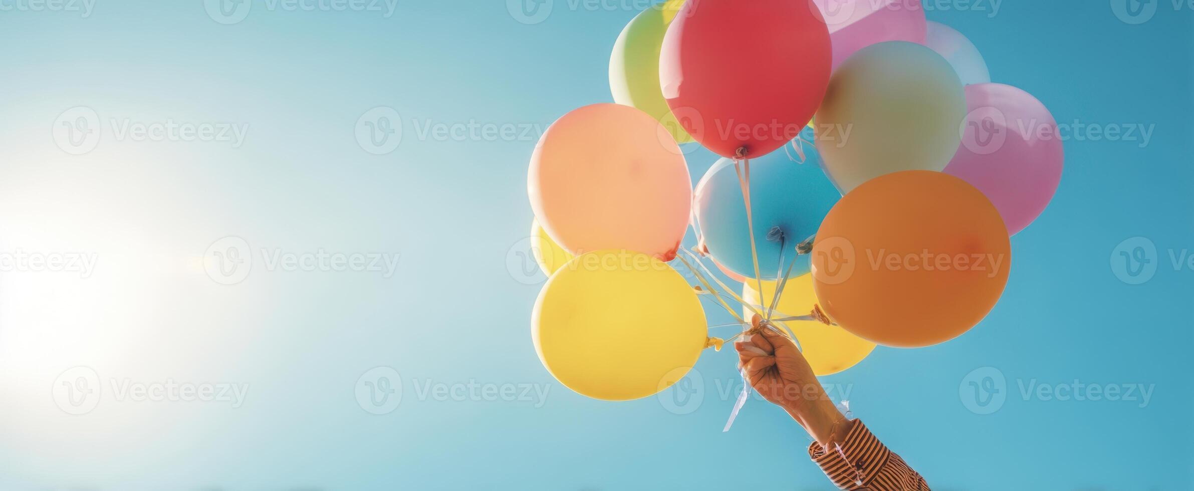 The vibrant array of balloons held high against a clear blue sky. photo