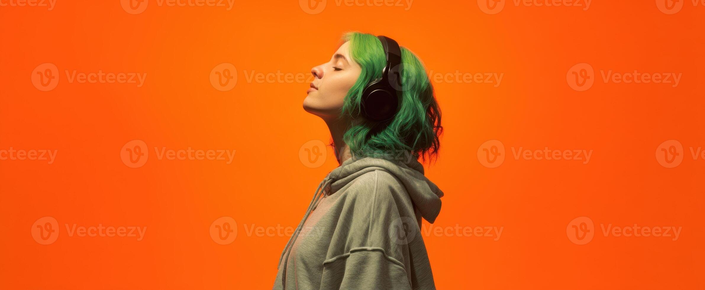 The woman with green hair enjoying music in a vibrant orange setting. photo