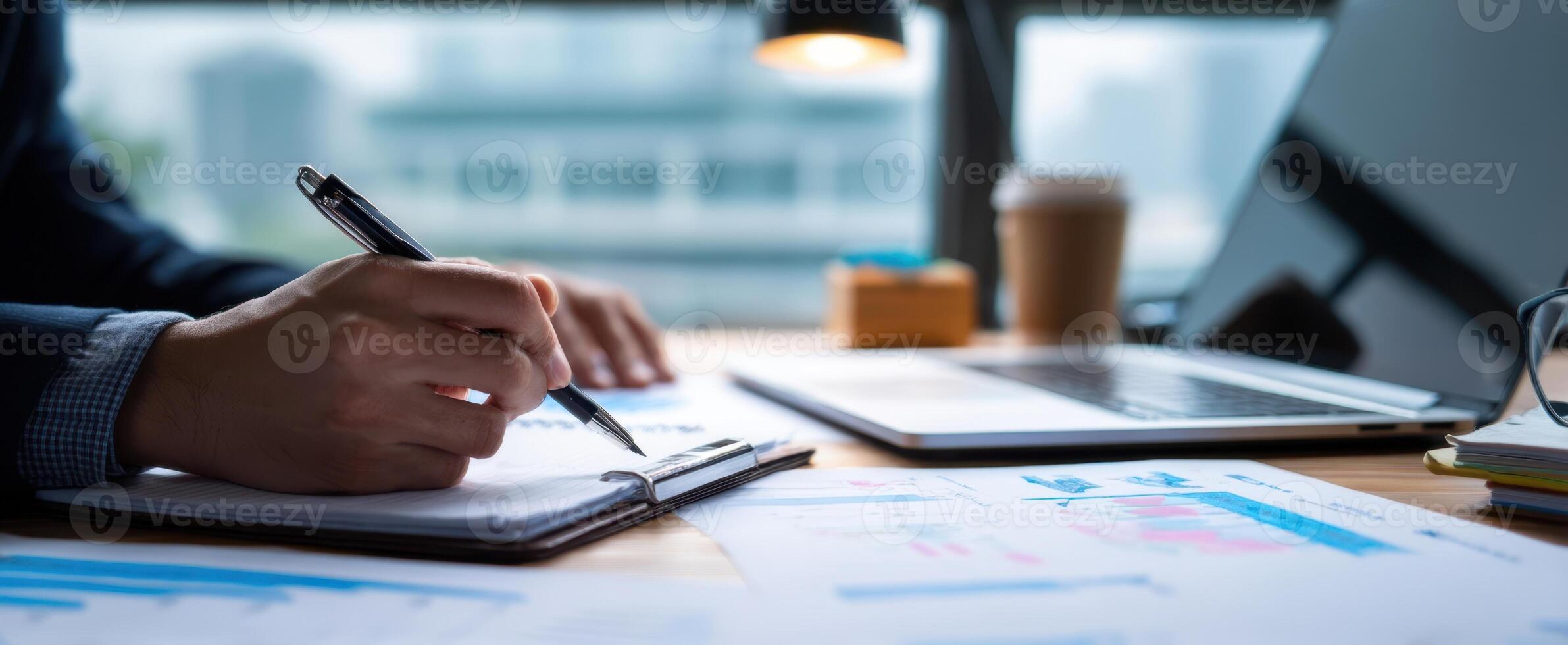 The focused hand writing notes on a business report at a modern desk. photo