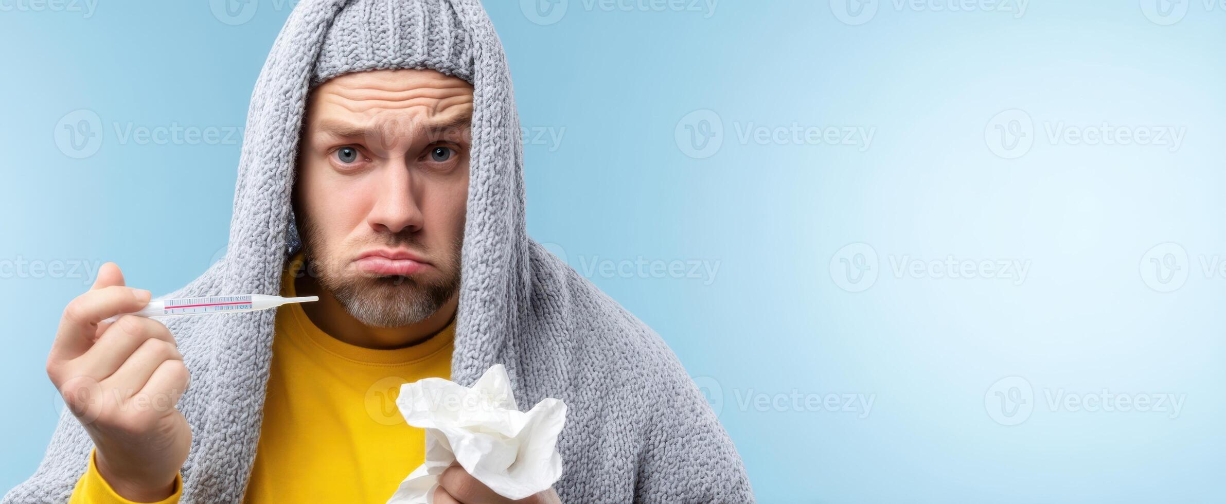 The sick man with a thermometer under a blanket looking worried and uncomfortable. photo