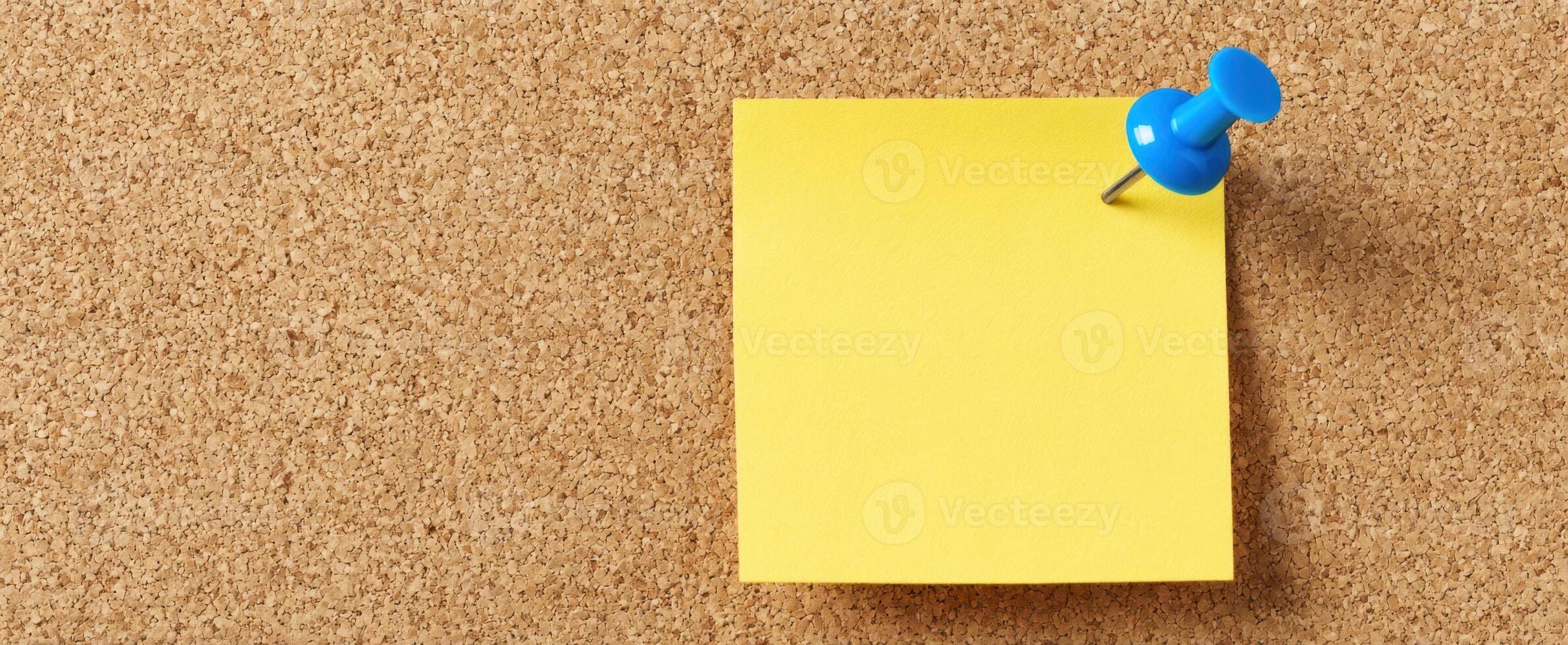 The yellow sticky note pinned on a corkboard background for reminders. photo